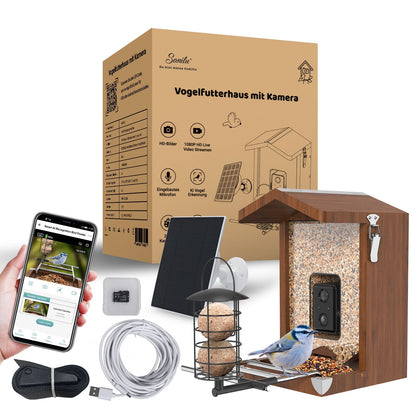Vogelfutterhaus mit eingebauter Kamera (sichtbare Kameralinse) in Holzoptik, Innenseite mit Körnern, Solarpanel, Montagehalterung, Meisenknödelhalter, USB-Kabel, Befestigungsband, Smartphone mit Live-Ansicht und Produktverpackung